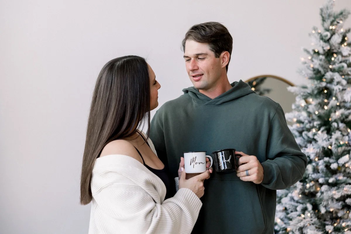Expecting couple holding Mom and Dad mugs at a cozy holiday mini session in Chicago
